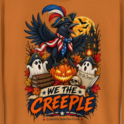 A close-up of an orange graphic print featuring a raven in a pirate hat and bandana, surrounded by a jack-o'-lantern, ghosts, autumn leaves, a haunted house, and the text 'WE THE CREEPLE' and 'Constitution Fan Club'.